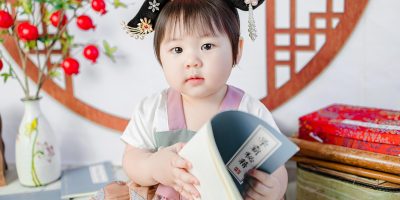 《彩云国物语》画面，身着古代中国宫廷服饰的少女站在华丽宫殿前，色彩鲜艳充满东方美感